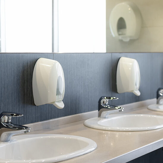 Public restroom with sinks faucets and mirror . Shallow DOF