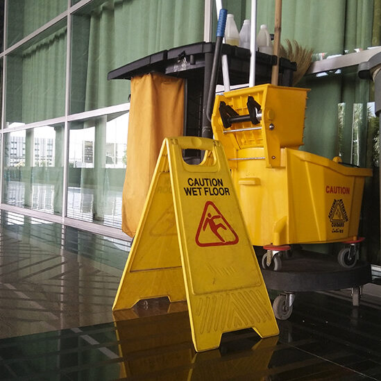 The warning signs cleaning and caution wet floor in the building and janitorial car parked in back to remind people to walk safely.